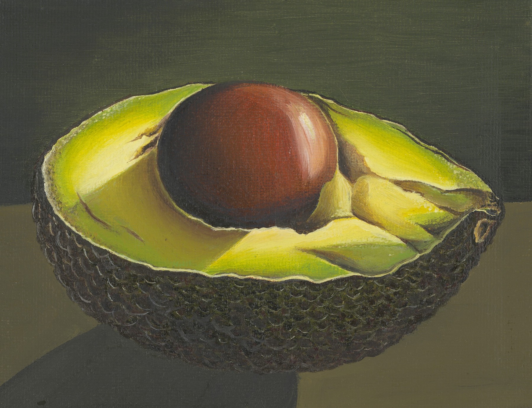 A halved avocado with bright yellow-green flesh, a large brown stone and textured dark skin against an olive background.
