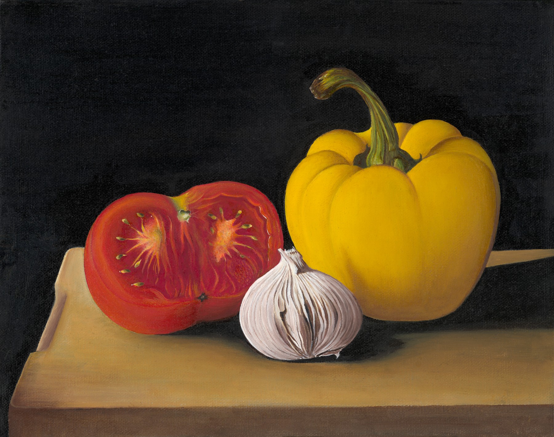 A halved red tomato, yellow pepper and white garlic bulb arranged on a wooden board against a dark background.